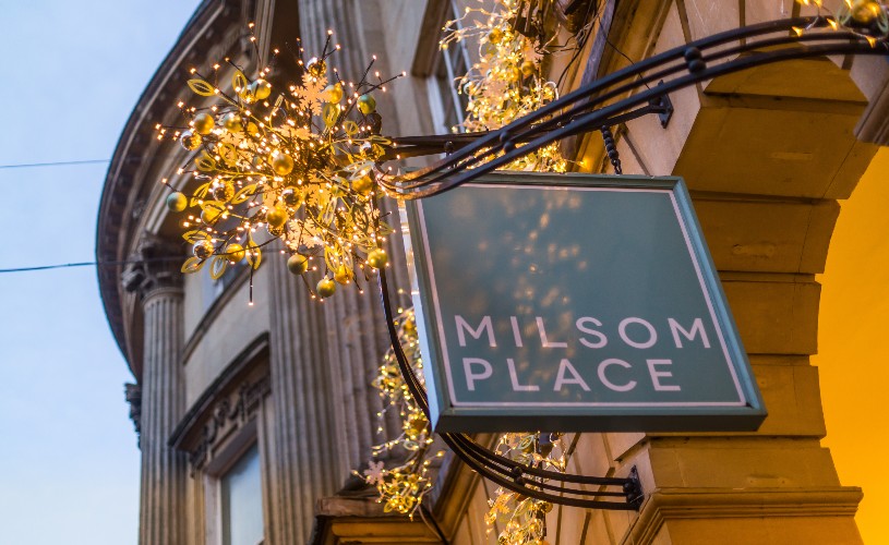 Christmas lights hanging by 'Milsom Place' sign